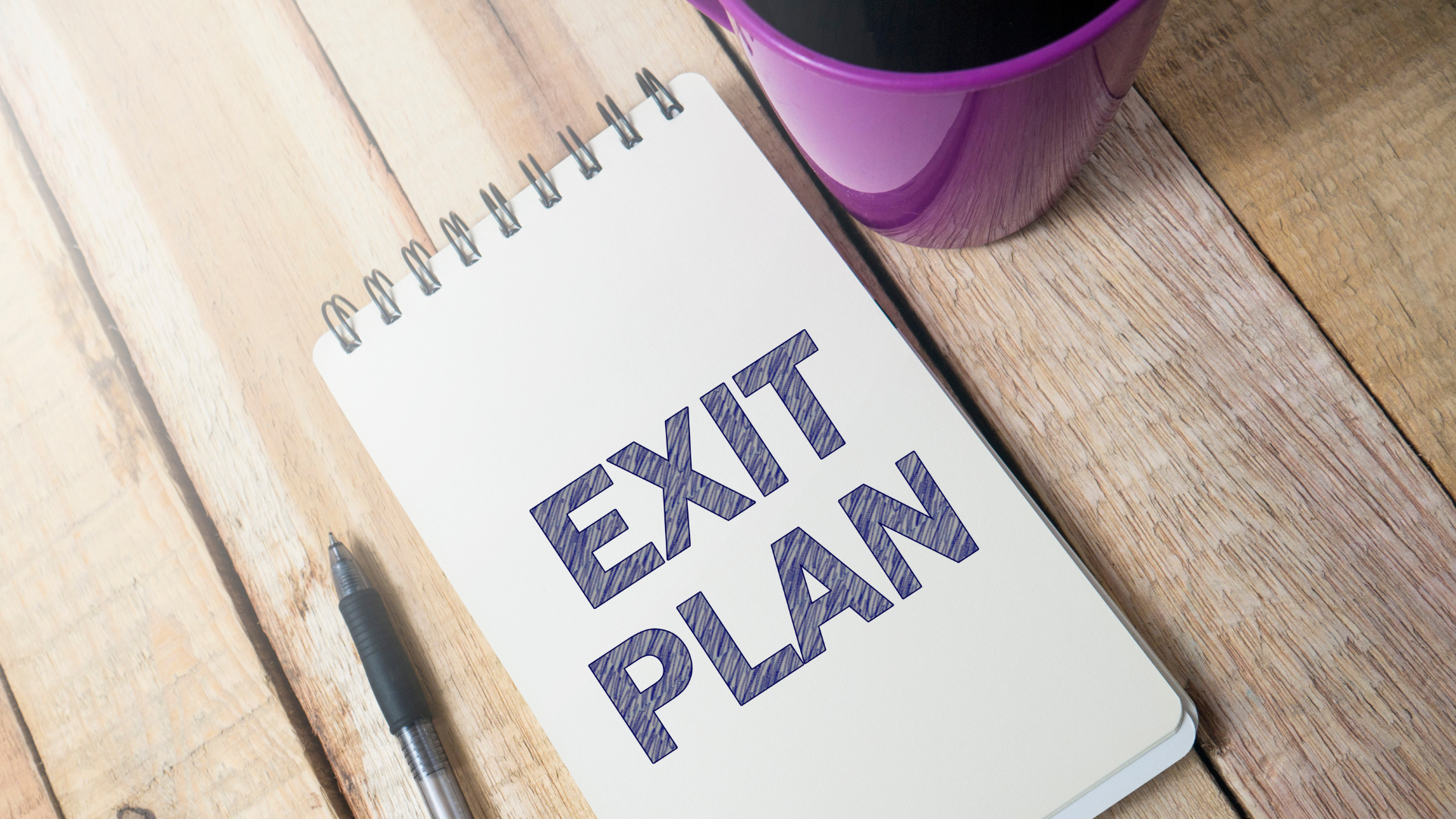 Unlock The Power - Online Presence Exit PlanLet's chat about your Online Presence Exit Plan notebook with EXIT PLAN written on front page, pen, coffee cup on wooden desk